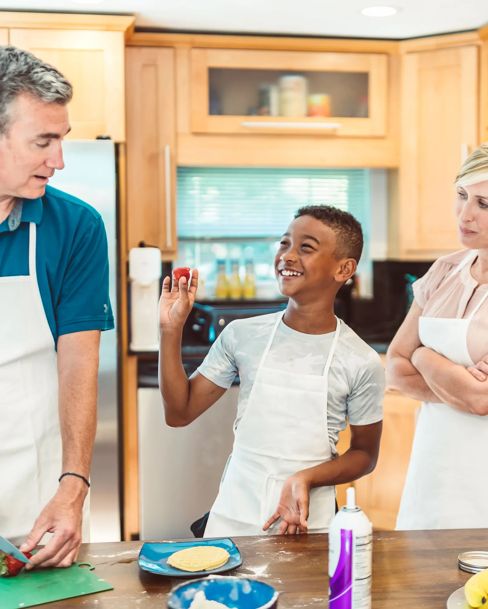 Des parents et leur enfant cuisinent ensemble dans une cuisine lumineuse